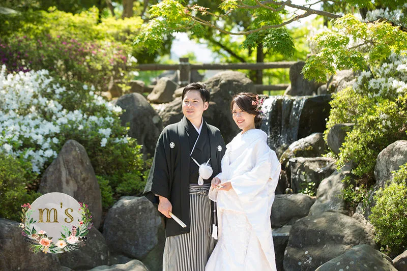 新緑の中で結婚写真を撮る白無垢姿と黒色の紋付袴の新郎新婦