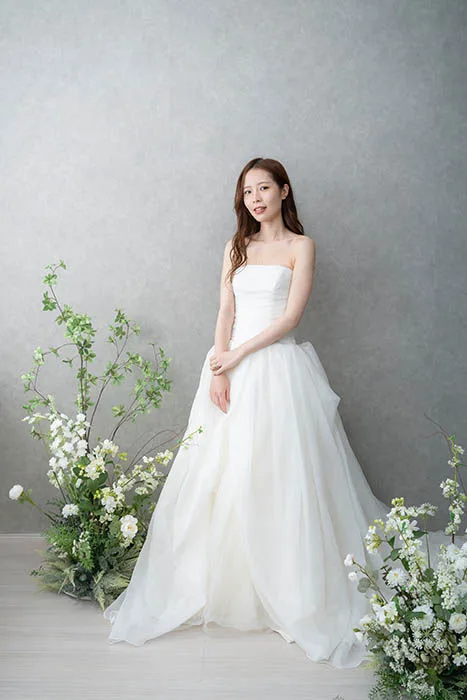 グリーンを添えたスタジオで、Vera Wang のAラインドレスを着た花嫁