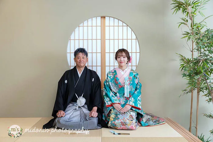 和室の丸窓前で正座する新郎新婦