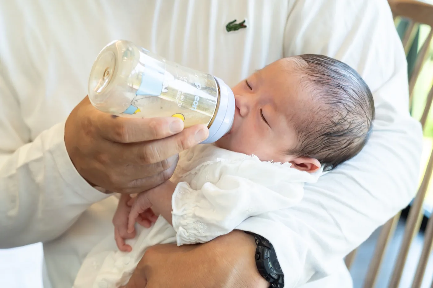父親の腕に抱かれて哺乳瓶からミルクを飲む赤ちゃん
